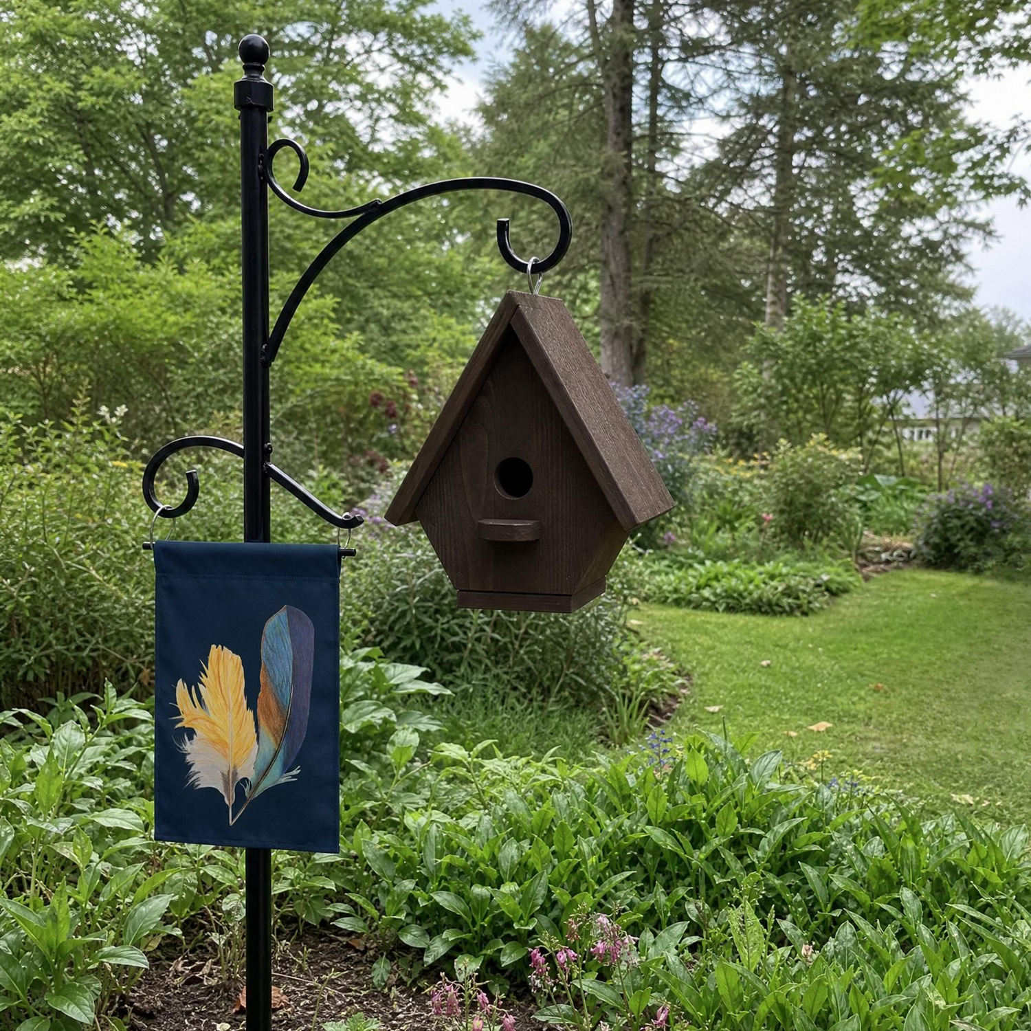 Brown birdhouse on a black metal stand with a decorative flag with hand drawn kingfisher feathers in a garden setting.