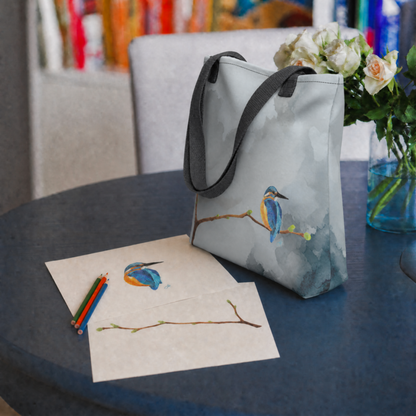 Tote bag with hand drawn kingfisher bird on a table next to a kingfisher drawing and colored pencils