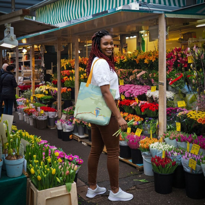 Woman shopping at a flower market with a hand drawn kingfisher tote bag